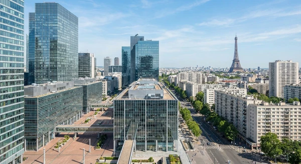 Vue aérienne ou urbaine de Paris montrant l'architecture moderne et les bâtiments de bureaux du quartier d'affaires, ou une rue parisienne typique avec immeubles haussmanniens, illustrant le contexte géographique professionnel où intervient l'entreprise de nettoyage. L'image doit être claire et reconnaissable comme étant Paris, en mettant l'accent sur l'environnement urbain et professionnel.